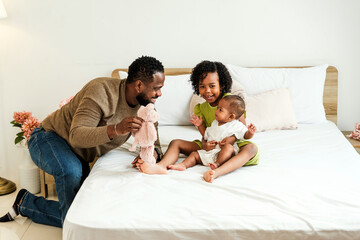 Joyful father plays with his daughters on a cozy bed, celebrating love and connection on Father’s...