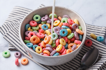 Colorful fruit cereal in bowl on white marble background.
