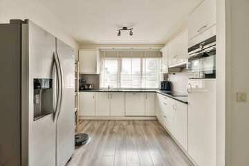 A sleek and contemporary kitchen featuring stainless steel appliances, minimalist cabinetry, and natural light streaming through the window, creating an inviting atmosphere.