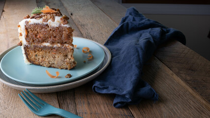 Slice of delicious carrot cake topped with cream cheese frosting, pecan pieces, and shaved carrot...