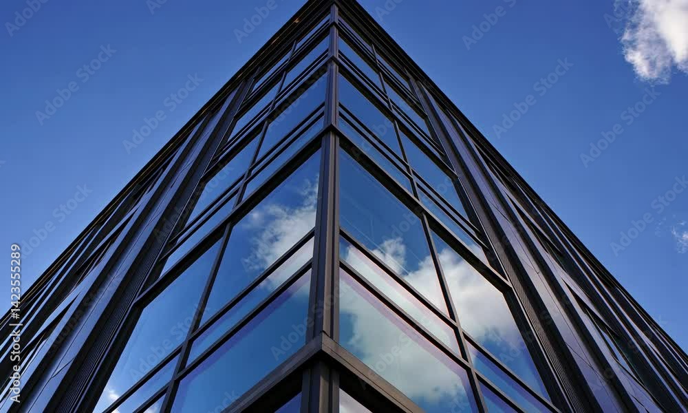 Poster modern glass building against clear blue sky from a dynamic low angle perspective, featuring angular