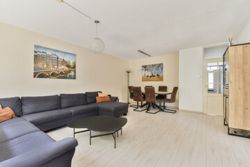 A cozy modern living room featuring a stylish couch, a decorative painting, and a dining area, showcasing contemporary design and comfort.