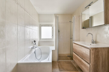 A sleek and modern bathroom featuring a bathtub, shower, and vanity with a clean aesthetic. Natural light filters in through the window, creating an inviting atmosphere.