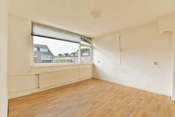 A vacant room featuring a large window that allows natural light to flood in. The simple design enhances spaciousness with clean lines and light wood flooring.
