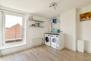 Bright and airy laundry room featuring modern appliances, shelves for storage, and a large window for natural light.