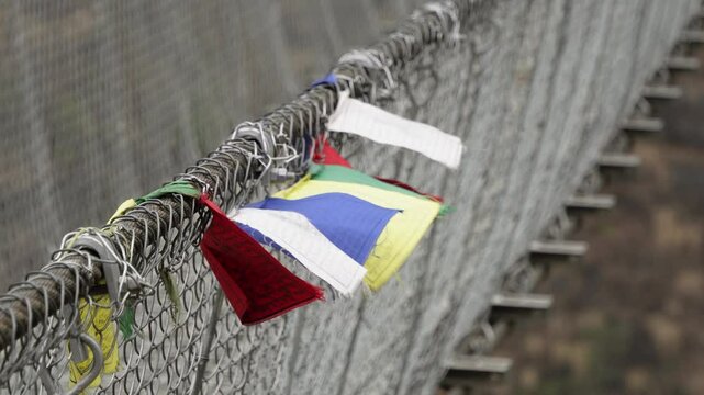Colorful prayer flags attached on Jhinu Danda suspension bridge fence at Annapurna Base Camp trek, Nepal.
