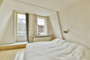 A sleek, minimalistic bedroom featuring a cozy bed, natural light streaming through large windows, and a clean aesthetic that promotes tranquility.