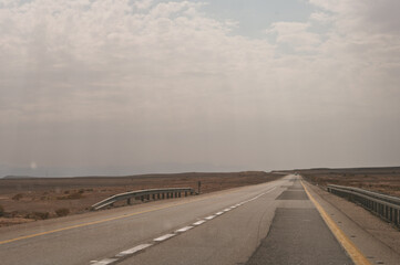 Fototapeta premium A long, empty road with a few cars in the distance