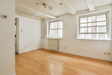 An airy and spacious interior featuring minimalist design, pale wooden flooring, and large windows that invite natural light.
