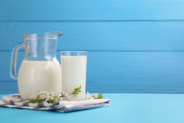 Fresh milk and blossoms on light blue table. Space for text