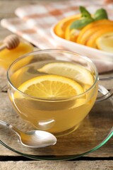 Aromatic fruit tea in glass cup, orange, lemon and honey on wooden table, closeup