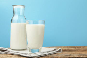 Fresh milk on wooden table against light blue background, closeup. Space for text