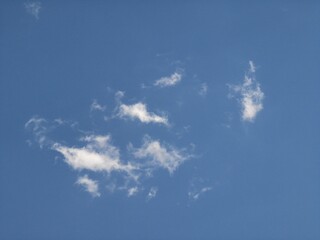 Light and fragmented wispy clouds dispersed across a deep blue sky, forming a minimal and serene background with open, airy atmosphere