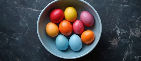Colorful Easter eggs in bowl on dark marble