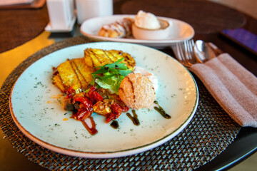 Potato pancakes and vegetables in caramel sauce with a scoop of pistachio ice cream