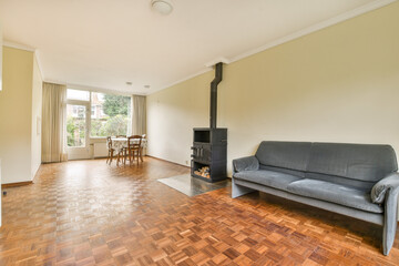 A spacious modern living room featuring a cozy fireplace, elegant wooden flooring, and large windows allowing natural light to fill the space.