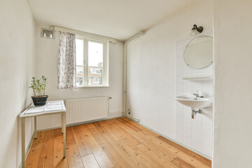 A serene and bright interior space featuring hardwood flooring, a small table, and a clean aesthetic with a stylish mirror and sink. Natural light enhances the atmosphere.