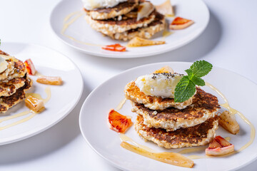 Healthy, dietary breakfast. Cottage cheese pancakes with cream cheese, orange, honey and mint on a white plate and background.