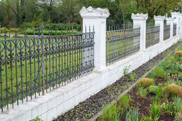 Wrought iron fence protecting lush green garden in spring