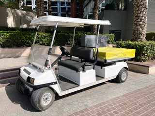 Golf cart parked on the sidewalk. Urban mobility, green transport, facility management in commercial, residential areas.