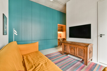 A stylish interior featuring a vibrant orange sofa, teal accent wall, wooden furniture, and sleek television setup, creating a cozy yet modern ambiance.