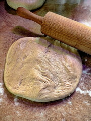 flat rolled khychiny dough with onion, cheese, and potato filling, ready to be rolled with a rolling pin on a prep surface