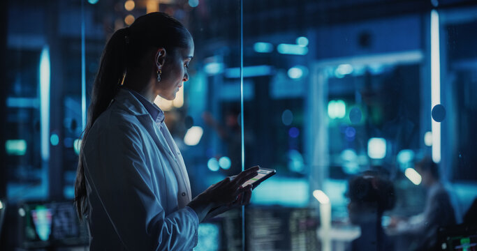Female Manager Using a Tablet Computer in a Scientific Office, Overseeing Quantum Computing Operations. Diverse Engineers Work Together on Artificial Intelligence Data and Analysis