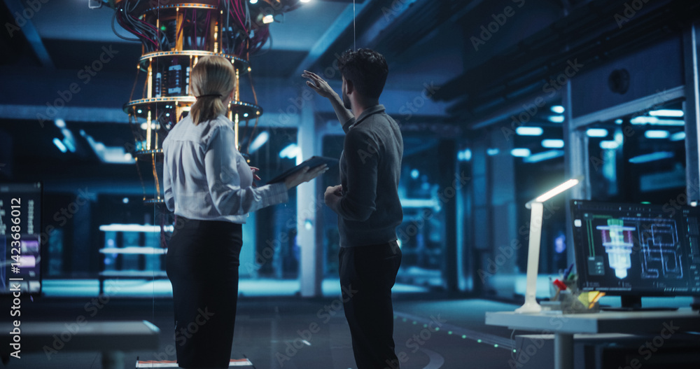 Poster portrait of engineers standing in a research center, using a tablet next to a powerful quantum proce