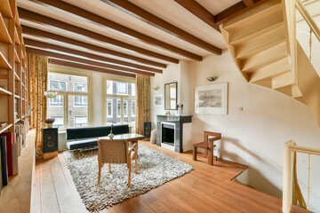 A stylish and modern living room featuring wooden beams, a cozy rug, and a staircase, creating a warm and inviting atmosphere for relaxation or socializing.