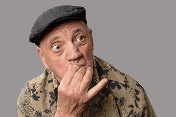 portrait homme âgé avec béret sceptique sur fond gris