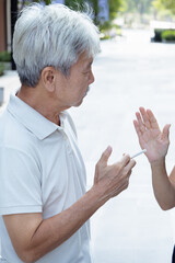 Old Asian senior man being asked to refrain from smoking, concept image for no smoking, smoking...