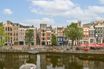 A picturesque view of historical canal houses lining the waterway in Amsterdam, showcasing vibrant architecture and lush greenery.