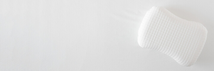 White soft memory foam pillow on mattress cloth background. Closeup. Wide banner. Empty place for text. Top down view.