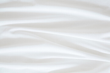 White wavy bed sheet background. Closeup. Top down view.