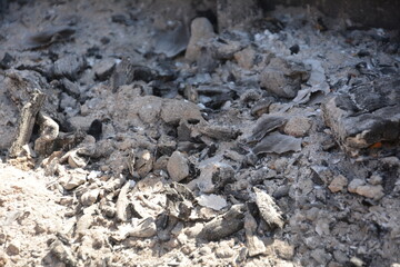 Fine white ash with small pieces of burnt wood after a fire