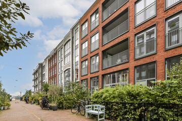 A scenic view showcasing a modern residential area lined with greenery, featuring stylish apartments and bike-friendly paths under a bright sky.