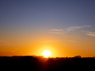 Sunrise, golden sunrise over a rural landscape in Brazil with trees in silhouettes and a bright sky on an autumn morning, natural light, selective focus.