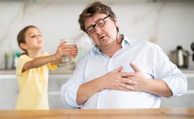 Fototapeta premium My father heart ached. Little daughter gives her father glass of water