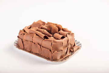 Chocolate cake, close up of a chocolate cake decorated with rolled chocolate shavings and sprinkled cocoa truffles on a silver tray with a white background, selective focus.