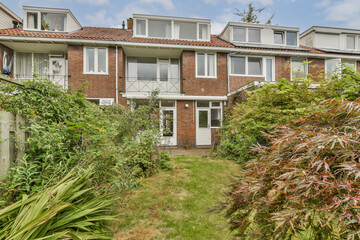 A picturesque brick house featuring a lovely garden with vibrant plants and trees, creating a serene atmosphere for relaxation and outdoor enjoyment.