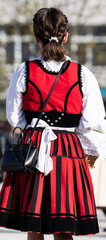 back of a szelker dressed girl in traditional red and black dress waiting for easter blessing
