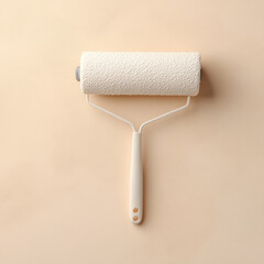 Obraz premium paint roller with textured white cover rests on smooth beige surface, showcasing its practical design for painting tasks. This evokes sense of creativity and home improvement