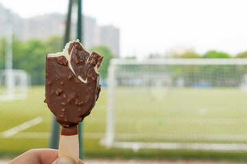 Obraz premium holding a chocolate popsicle in front of a soccer field