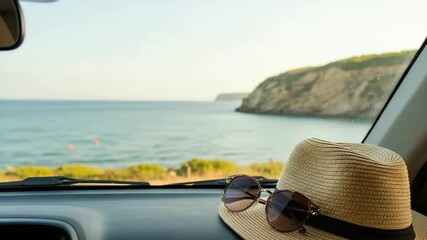 Straw hat and sunglasses on car dashboard with coastal cliffs and sea view, relaxed summer vacation atmosphere for travel content