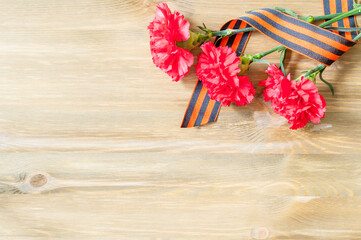 9 May background for Victory Day holiday. Three red carnations and St George ribbon lying on the...