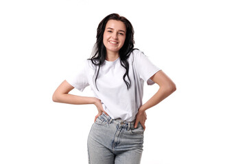 Young woman poses confidently in casual outfit with white t-shirt and blue jeans in studio setting
