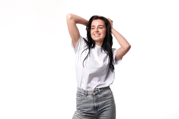 Young woman posing happily with hands in hair against a solid white background in a casual outfit