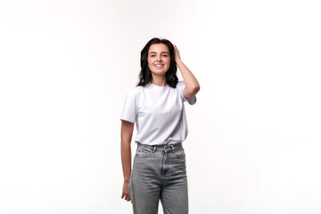 Young woman smiles while posing in studio with plain white background, showcasing casual fashion...