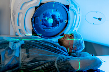 A young man undergoing radiation therapy for cancer in a state-of-the-art oncology clinic using a...