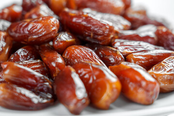 Dried dates in glass plate on white table. Macro shot. Front view
